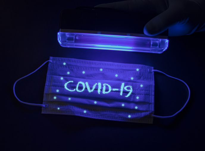 Protective medical mask with Covid-19 and small coronavirus molecules under an ultraviolet lamp 